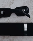 Black sunglasses from E1 Equestrian with a reflective lens on a textured surface