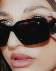 Close-up of a person wearing black sunglasses with E1 Equestrian brand logo.
