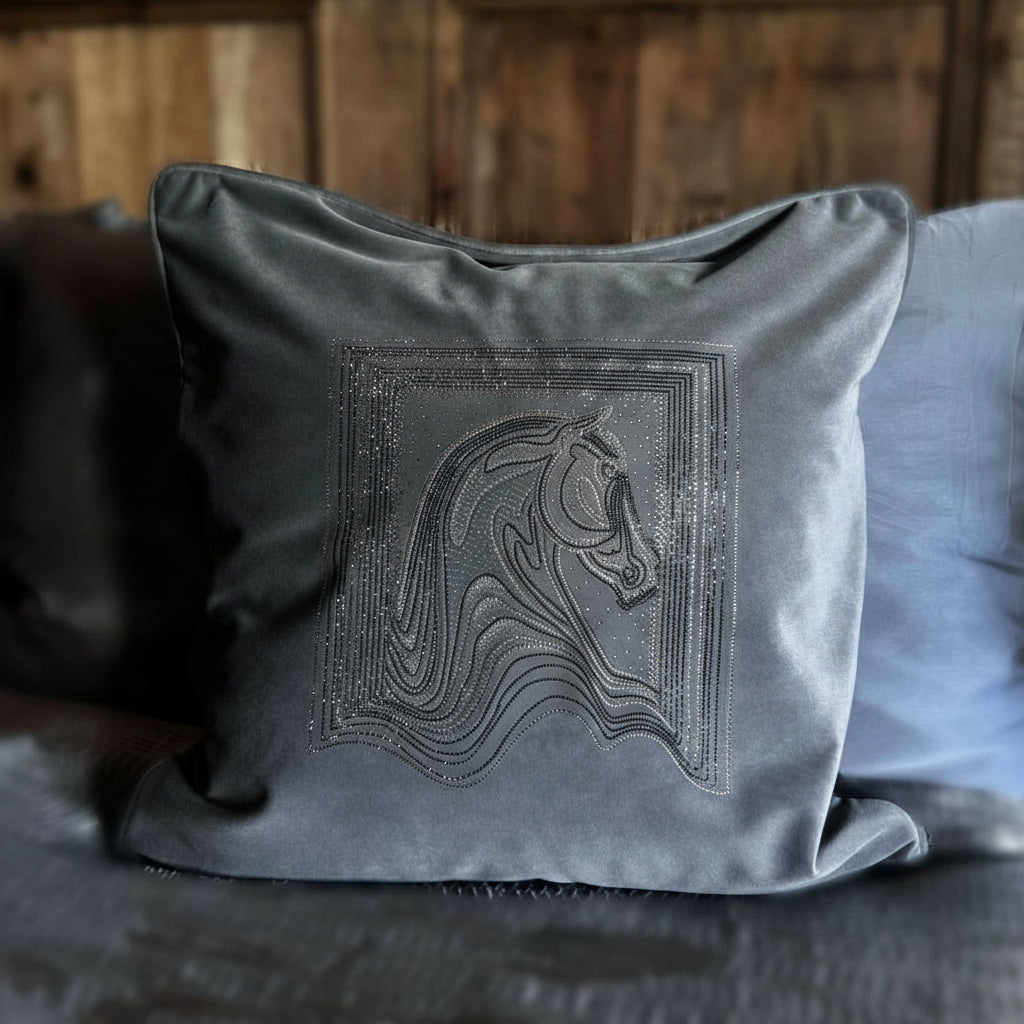 Gray pillow with unicorn embroidery on a bed with wooden headboard