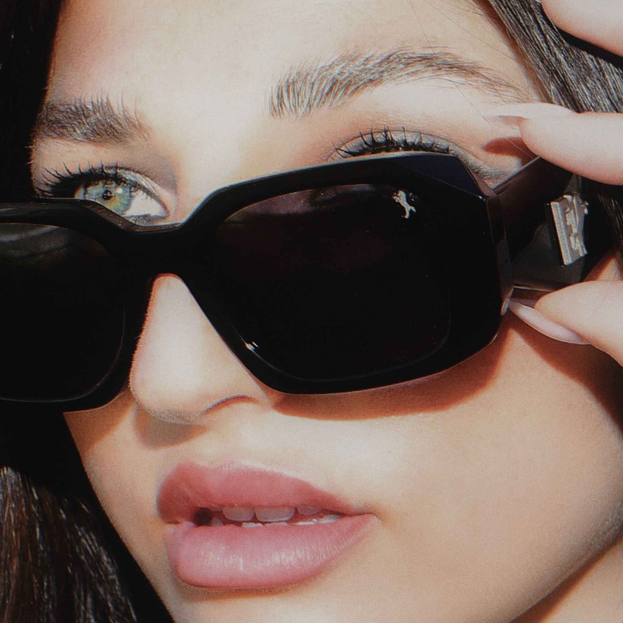 Close-up of a person wearing black sunglasses with E1 Equestrian brand logo.